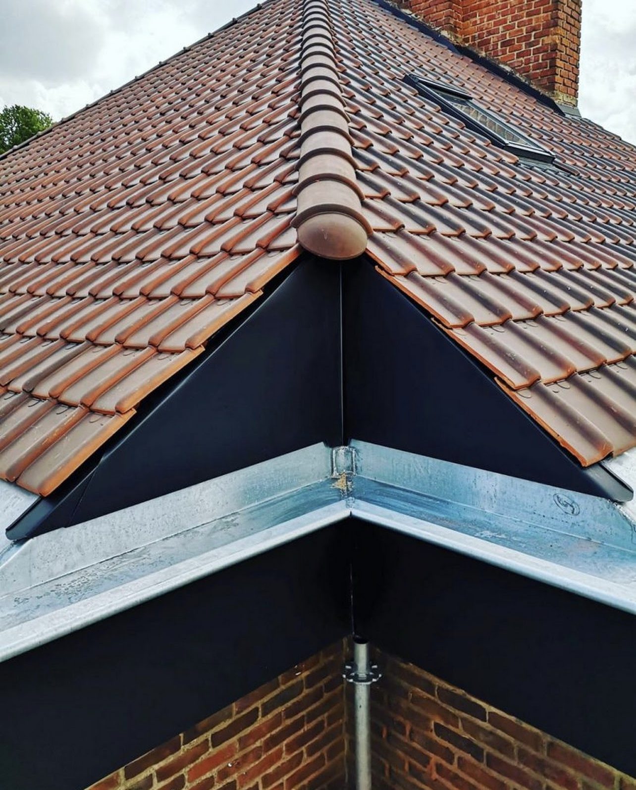 Détail noue zinc neuve raccordée aux tuiles vernissées